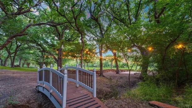 A wooden bridge over a gravel path in a park with trees and string lights. - The Redwood Estate - Events on 25 Acres of Serenity (Aubrey)