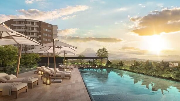 A rooftop pool area with lounge chairs and umbrellas, surrounded by lush greenery and a view of distant mountains. - Deluxe apartment near the Airport entire rental unit (Guatemala)