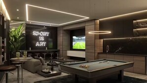 A modern living room with a pool table, bar area, and a large TV screen displaying a sports game. - Deluxe apartment near the Airport entire rental unit (Guatemala)