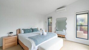 A modern bedroom with a bed, nightstands, a mirror, and large windows. - Sea Views set atop a hill in Kiama (Kiama)