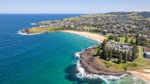 An aerial view of a coastal town with a beach, residential areas, and a hilly landscape in the background. - Sea Views set atop a hill in Kiama (Kiama)