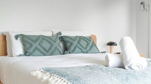 A neatly made bed with a white comforter, two pillows with a geometric pattern, a rolled towel, and a bedside lamp. - Sea Views set atop a hill in Kiama (Kiama)