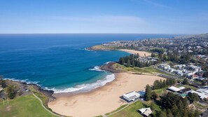An aerial view of a coastal town with a sandy beach, residential areas, and a clear blue sky. - Sea Views set atop a hill in Kiama (Kiama)