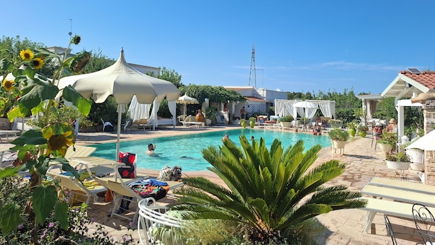 A pool area with sun loungers, umbrellas, and a clear blue sky. - 4 minutes from the historic center of Ostuni Family apartment with swimming pool (Ostuni)