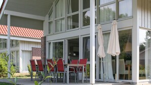 Un bâtiment moderne doté de grandes fenêtres et d’un patio couvert avec des espaces de détente en plein air.