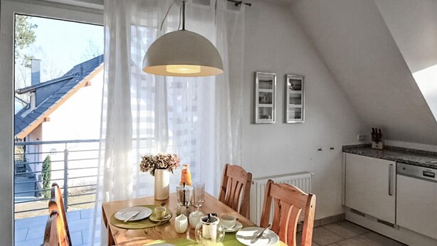 Een eethoek met een houten tafel voor vier personen, een hanglamp en uitzicht op het exterieur.