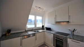 Een moderne keuken met raam, roestvrijstalen apparatuur en witte kasten.