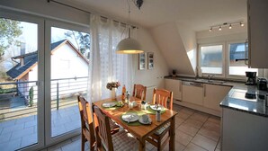 Een moderne keuken met een eethoek, grote ramen en uitzicht op buiten.