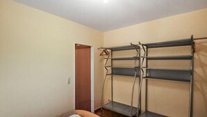 Une pièce avec un lit superposé, une porte et une étagère en métal.
