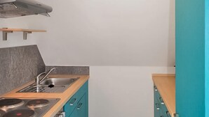 Eine moderne Küche mit Gaskochfeld, Spüle und Türkis-Schränken.