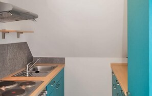 Eine moderne Küche mit Gaskochfeld, Spüle und Türkis-Schränken.