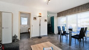Ein modernes Wohnzimmer mit Essbereich, großen Fenstern und Blick ins Freie.