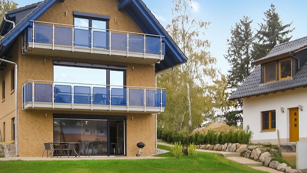A two-story house with a balcony, a patio with outdoor furniture, and a small garden area. - 1 bedroom pet friendly apartment in Röbel (Röbel)