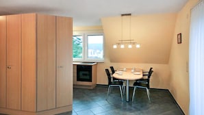 A dining area with a round table, chairs, a built-in oven, and a window with a view of houses. - 1 bedroom pet friendly apartment in Röbel (Röbel)