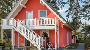 A red house with a white balcony and stairs leading to the entrance. - Lovely apartment in Röbel with sauna (Röbel)