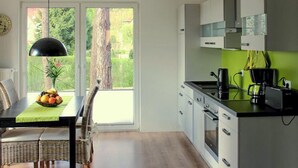 A modern kitchen with a dining area, a view of trees, and a clock on the wall. - Lovely apartment in Röbel with sauna (Röbel)