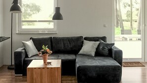 A modern living room with a dark grey sectional sofa, a wooden coffee table, and a potted plant. - Lovely apartment in Röbel with sauna (Röbel)