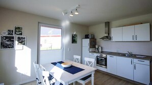 A compact kitchen with white cabinets, a dining table with chairs, a microwave, a stove, and a window with a view of the outside. - Amazing apartment in Röbel with sauna (Röbel)