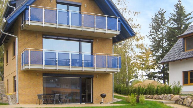 A two-story house with a balcony, a sliding glass door, and a barbecue grill in the yard. - 1 bedroom beautiful apartment in Röbel (Röbel)
