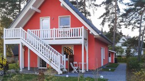 Una casa roja con un balcón blanco y una escalera que lleva a la entrada.