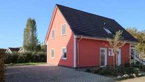 Ein zweistöckiges Haus mit roter Fassade und dunklem Dach.