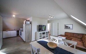 Un espacio habitable compacto con kitchenette, comedor y zona de estar.
