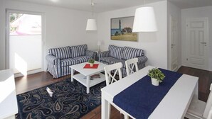 Ein Zimmer mit einer gestreiften Sofagarnitur, einem weißen Tisch und einem blauen Teppich.