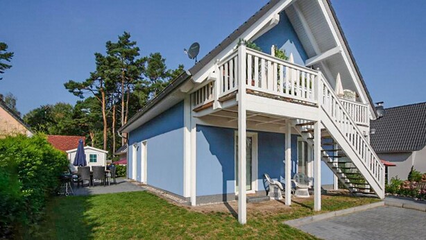 Ein zweistöckiges Haus mit einem Balkon und einer Treppe, die zum oberen Stock führt.
