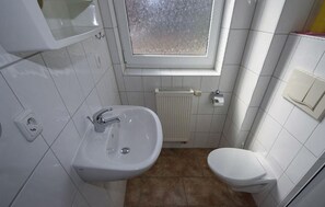 A small, clean bathroom with a white sink, a toilet, and a window above the sink. - Stunning apartment in Röbel with lake view (Röbel)