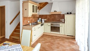 Una cocina compacta con una escalera, un comedor y una ventana con cortinas.