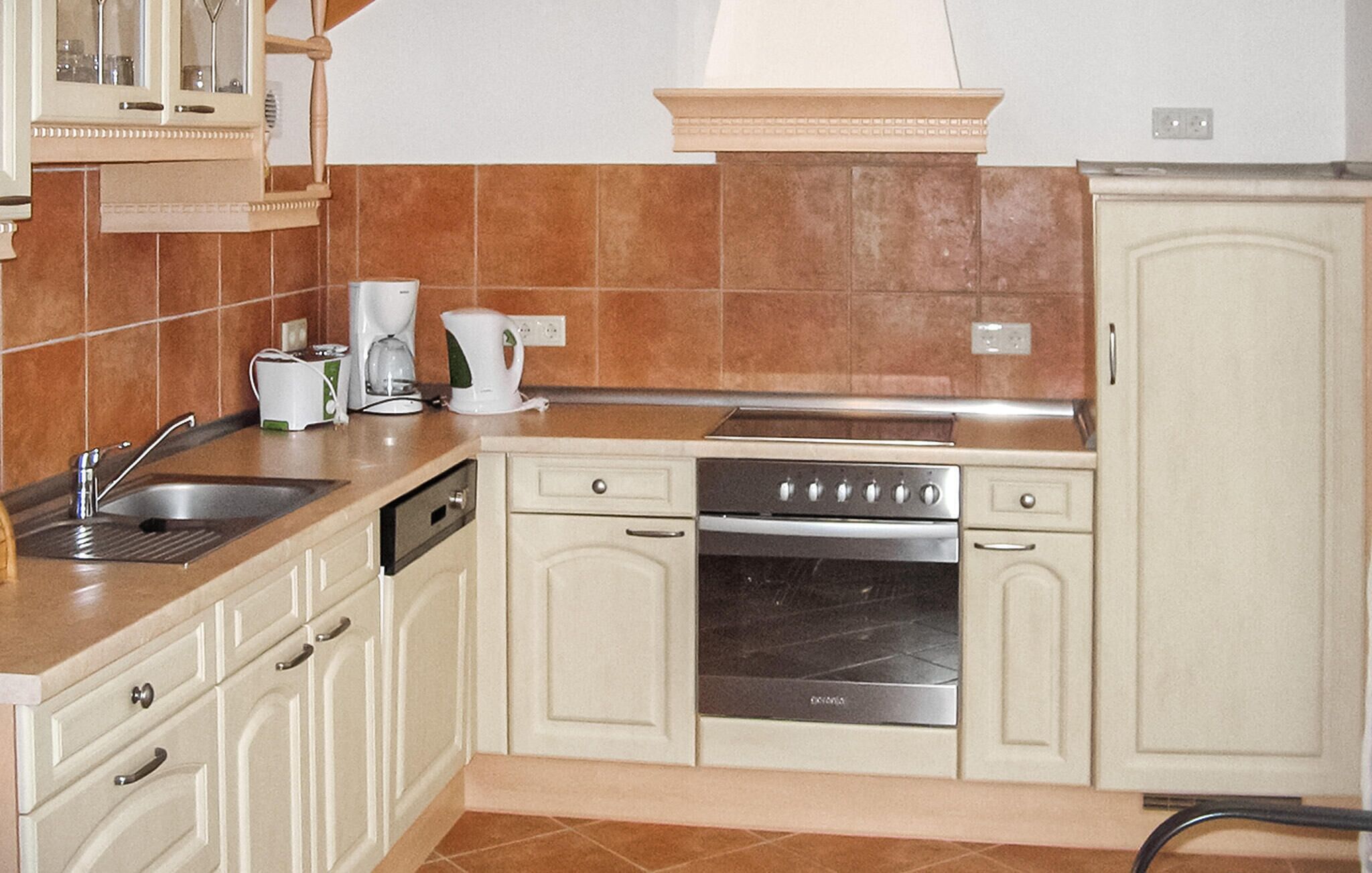 A kitchen with a sink, dishwasher, stove, and cabinets.