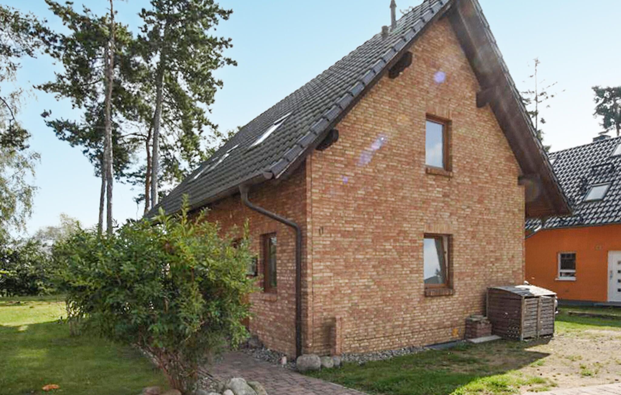 Een bakstenen huis met schuin dak en een kleine tuin.