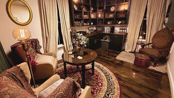 Una sala de estar acogedora con una mesa redonda, dos sillones, un sofá, una estantería y una zona de cocina.