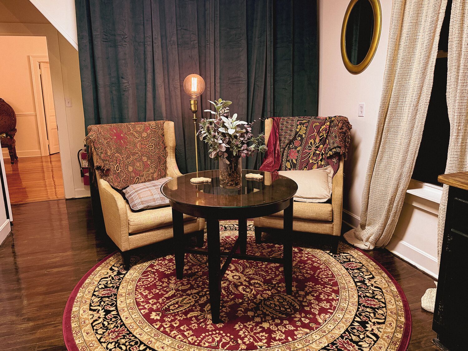 A cozy living room with two armchairs, a round coffee table, and a decorative rug.