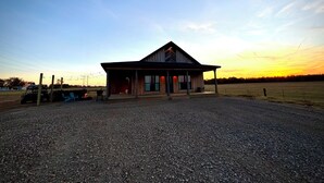 A rustic building with a porch, a covered outdoor area, and a gravel driveway. - Duck hunting cabin (Newport)