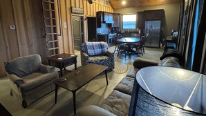A cozy, rustic interior with a dining area, kitchen, and seating space. - Duck hunting cabin (Newport)