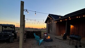 A rustic outdoor setting with a wooden chair, a fire pit, and a barbecue grill. - Duck hunting cabin (Newport)
