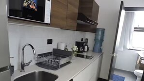 Uma cozinha moderna com eletrodomésticos de aço inoxidável, escorredor de louça e um bebedouro.