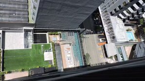 Un edificio alto con piscina sul tetto, un prato verde e un’area parcheggio.