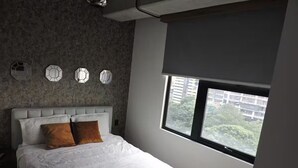Una camera da letto con un letto, una finestra vista edifici e un muro con texture.
