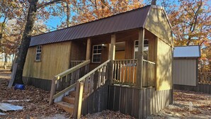A wooden cabin with a porch and a staircase leading to the entrance.