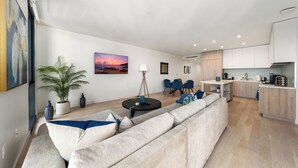A modern living room with a sofa, a dining area, and a kitchen. - The Sapphire Nest' Luxury Condo Walk to Beach & Pier Rooftop Pool, Gym Parking (Santa Monica)