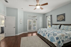 A bedroom with a bed, a ceiling fan, a door, and a window with blinds. - 5BR Pool Retreat with Lanai, Fire Pit & Bikes (Palm Coast)