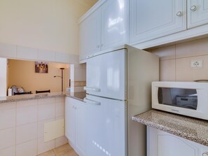 A modern kitchen with white cabinetry, a built-in microwave, and a granite countertop. - Pine Retreat (Vilamoura)
