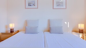 Ett hotellrum med två sängar, var och en med ett vitt sängöverkast och matchande kuddar. Det finns inramade tavlor på väggen ovanför sängarna.