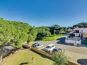 A residential area with parked cars, a stone wall, and a house with a red roof. - Pine Retreat (Vilamoura)