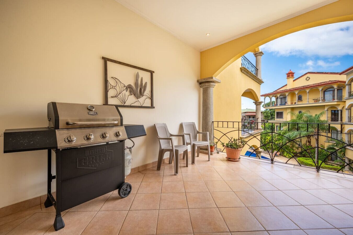 Ein Balkon mit Grill, Stühlen und einem Blumentopf.
