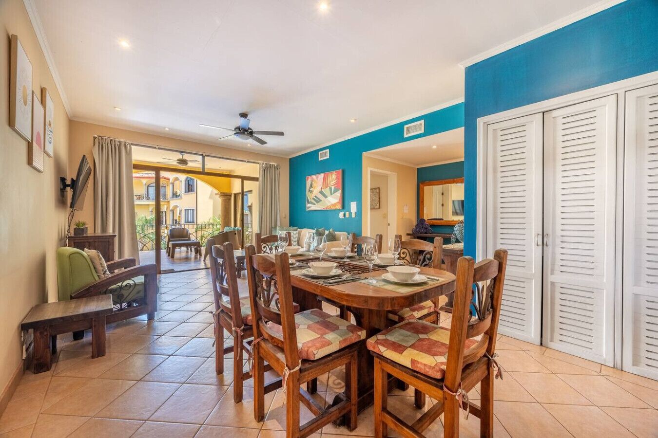 A dining area with a large table set for four, surrounded by wooden chairs with cushioned seats.