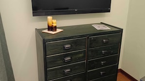 Een donkere houten dressoir met meerdere lades en een flatscreen televisie erboven bevestigd.