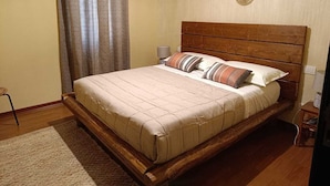 Een slaapkamer met een houten bed, een nachtkastje, een lamp en een wand met decoratieve borden.